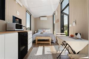 a small bedroom with a bed in a room with windows at Hillside Hideout by Tiny Away in West Kentish