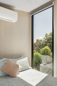 a bedroom with a bed and a large window at Hillside Hideout by Tiny Away in West Kentish
