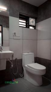 a bathroom with a white toilet and a sink at Casawyna Family Retreat Centre in Wayanad