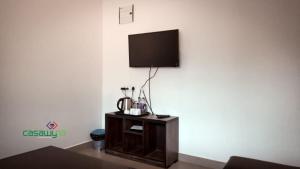 a room with a tv on a wall with a table at Casawyna Family Retreat Centre in Wayanad