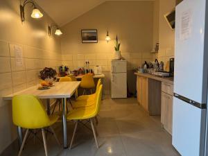 a kitchen with a table and yellow chairs at Willa Ogrodnika in Błażowa