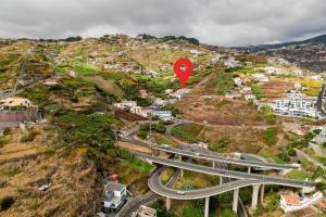 a red sign on a hill with a highway at Cris Place in Câmara de Lobos