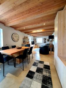 une salle à manger avec une table, des chaises et une horloge dans l'établissement Casa Sandra Moena by Go new Location, à Moena