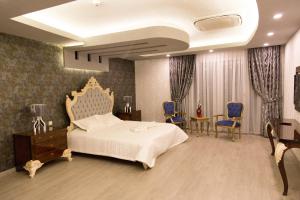 een slaapkamer met een groot bed en blauwe stoelen bij Carmine Otel in Kırıkkale