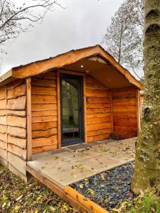 Cabaña de madera con porche y puerta en 1 Bedroom Log Cabin in Parc Pen y Bryn Sleep 2 3, en Derwen 3 fotos más