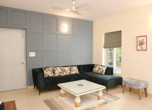 BardezCasa Cenica - 2bhk furnished apt, Arpora pool view的客厅里有一张黑色沙发和一张桌子