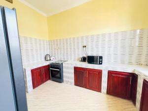 a kitchen with red cabinets and a black appliance at Vuga Hostel in Zanzibar City