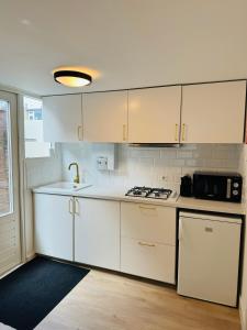 Una cocina con gabinetes blancos, un fregadero y un microondas. en Zomerhuis - Gratis parkeren!, en Noordwijk aan Zee