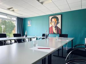 a conference room with tables and chairs and a painting at Le Pré Saint Germain in Louviers