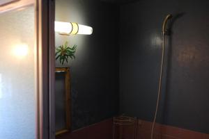ein Bad mit einem Spiegel und einer Lampe an der Wand in der Unterkunft 向島集会所夕朝二食付き in Naoshima