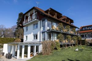 a large white house with a balcony at Hotel Haus am See in Nonnenhorn