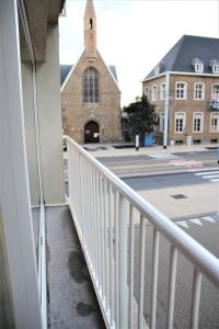 a balcony with a white railing and a church at Cosy gezellig app met aparte gastenkamer op 30meter van strand privé garage in Koksijde