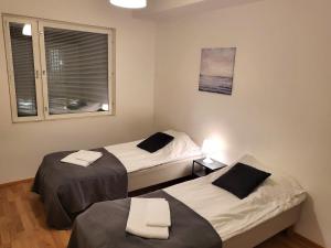two beds in a small room with a window at Kotimaailma - kodikas kolmio Espoossa in Espoo