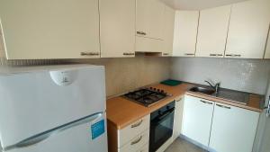a kitchen with white cabinets and a white refrigerator at P313 nr 102 trilocale sul mare con ombrellone in prima fila in Marcelli