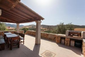 a patio with a table and a stone wall at Appartamento immerso nel verde in San Teodoro