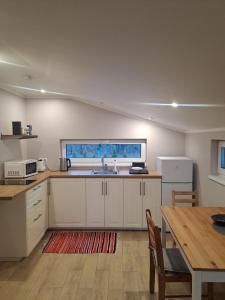 a kitchen with white cabinets and a table and a sink at Rožu ielas namiņš in Sigulda