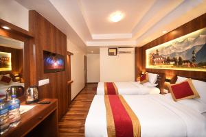 una camera d'albergo con due letti e una televisione di Hotel Friends Home a Kathmandu