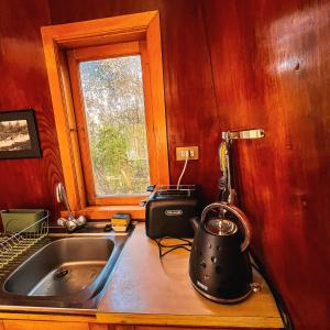 una cocina con fregadero y tetera en una encimera en Unique Tree House Hideaway in Nature, en Ancud