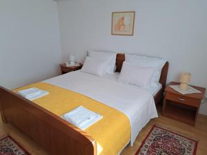 a bedroom with a bed with white sheets and two tables at Apartments Pink house in Povljana