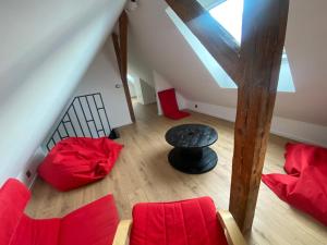 an attic room with red furniture and a table at Gîte de la Chapelle - Le Bi jou in Innenheim
