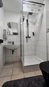 a bathroom with a shower and a sink and a tub at Hotel Essen mit Apartments in Essen