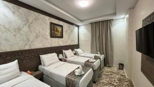 a hotel room with three beds and a flat screen tv at فندق زهرة الفرسان in Mecca +50 photos