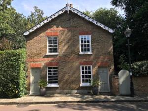 ein rotes Backsteinhaus mit weißen Fenstern und Pflanzen in der Unterkunft Charming Cottage with Roof Terrace in Twickenham