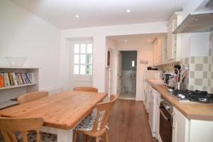 eine Küche mit einem Holztisch und einigen Stühlen in der Unterkunft Charming Cottage with Roof Terrace in Twickenham