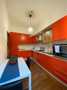 a kitchen with orange cabinets and a blue table and chairs at Roma 2 Apartment - THE V Collection in Turate +5 photos