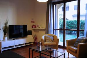 a living room with a flat screen tv and chairs at Roma 2 Apartment - THE V Collection in Turate