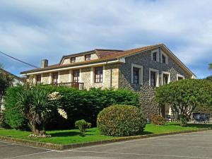 a large stone house with bushes and trees at Posada Playa de Langre in Langre