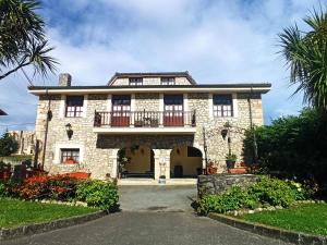 a large stone house with a balcony on a street at Posada Playa de Langre in Langre +25 photos