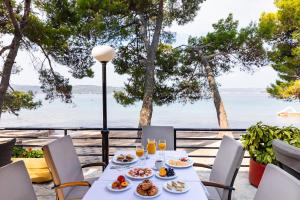 a table with food and drinks on a balcony overlooking the ocean at Camping Park Soline Pitches in Biograd na Moru