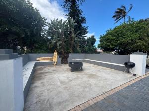 a patio with a bench and a surfboard on a wall at Ballito Holiday Home in Ballito