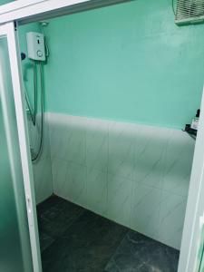 a bathroom with a shower with a white wall at Divine's Cabin, Fully Airconditioned! in Tacondo +5 photos