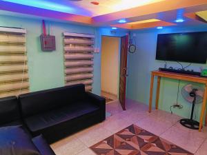 a living room with a couch and a flat screen tv at Divine's Cabin, Fully Airconditioned! in Tacondo