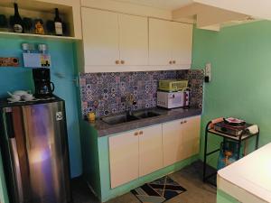 a kitchen with a sink and a refrigerator at Divine's Cabin, Fully Airconditioned! in Tacondo