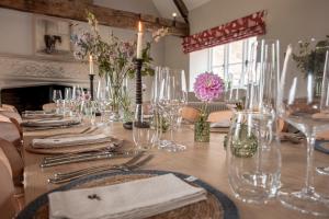 a table with glasses and vases on top of it at Brokenborough Farmhouse in Malmesbury