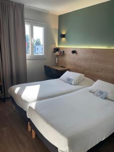 due letti in una camera d'albergo con finestra di Kyriad Montpellier Sud - A709 a Montpellier Altre 37 foto