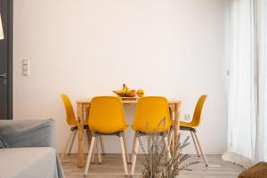 a dining room table with yellow chairs in a living room at Yara Apt 40m from the Beach Jacuzzi & Rooftop in Agia Anna Naxos