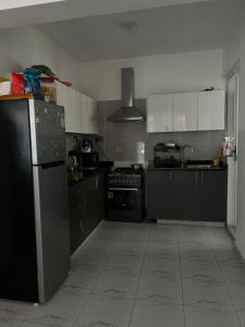 a kitchen with black cabinets and a black refrigerator at Secret Serenity - Modern, Stylish & Comfy 2 Bedroom Apartment With Workspace, Secure Parking, CCTV, Swimming Pool, Gym, And City Views in Nairobi in Nairobi
