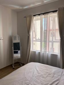 a bedroom with a bed and a window with a chair at Secret Serenity - Modern, Stylish & Comfy 2 Bedroom Apartment With Workspace, Secure Parking, CCTV, Swimming Pool, Gym, And City Views in Nairobi in Nairobi +12 photos
