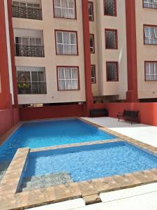 an empty swimming pool in front of a building at Secret Serenity - Modern, Stylish & Comfy 2 Bedroom Apartment With Workspace, Secure Parking, CCTV, Swimming Pool, Gym, And City Views in Nairobi in Nairobi