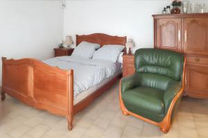 a bedroom with a bed and a green chair at Maison rustique charmante à Sassetot-le-Mauconduit, jardin. in Sassetot-le-Mauconduit