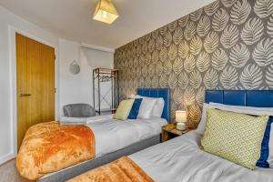a bedroom with two beds and a wall at Cosy Central 2-Bed Flat City View & Parking in Wigan