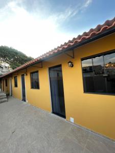 a yellow house with a lot of windows at Caverna Suítes - Suítes na praça matriz in São Thomé das Letras
