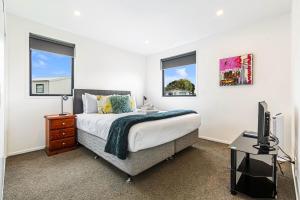 a bedroom with a bed and a tv and windows at Auckland airport homes six minutes from airport three bedrooms two and half bathrooms in Auckland