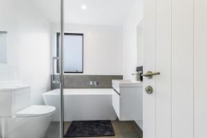 a white bathroom with a toilet and a sink at Auckland airport homes six minutes from airport three bedrooms two and half bathrooms in Auckland +15 photos