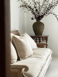 a couch with pillows and a vase on a table at Poem House Bali in Munggu