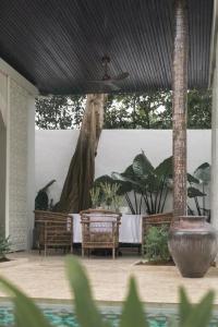a patio with a table and chairs and a ceiling at Poem House Bali in Munggu